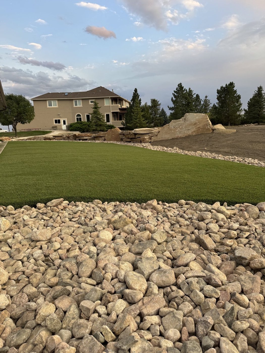 Artificial turf edge against a rock border, infill visible at the seam