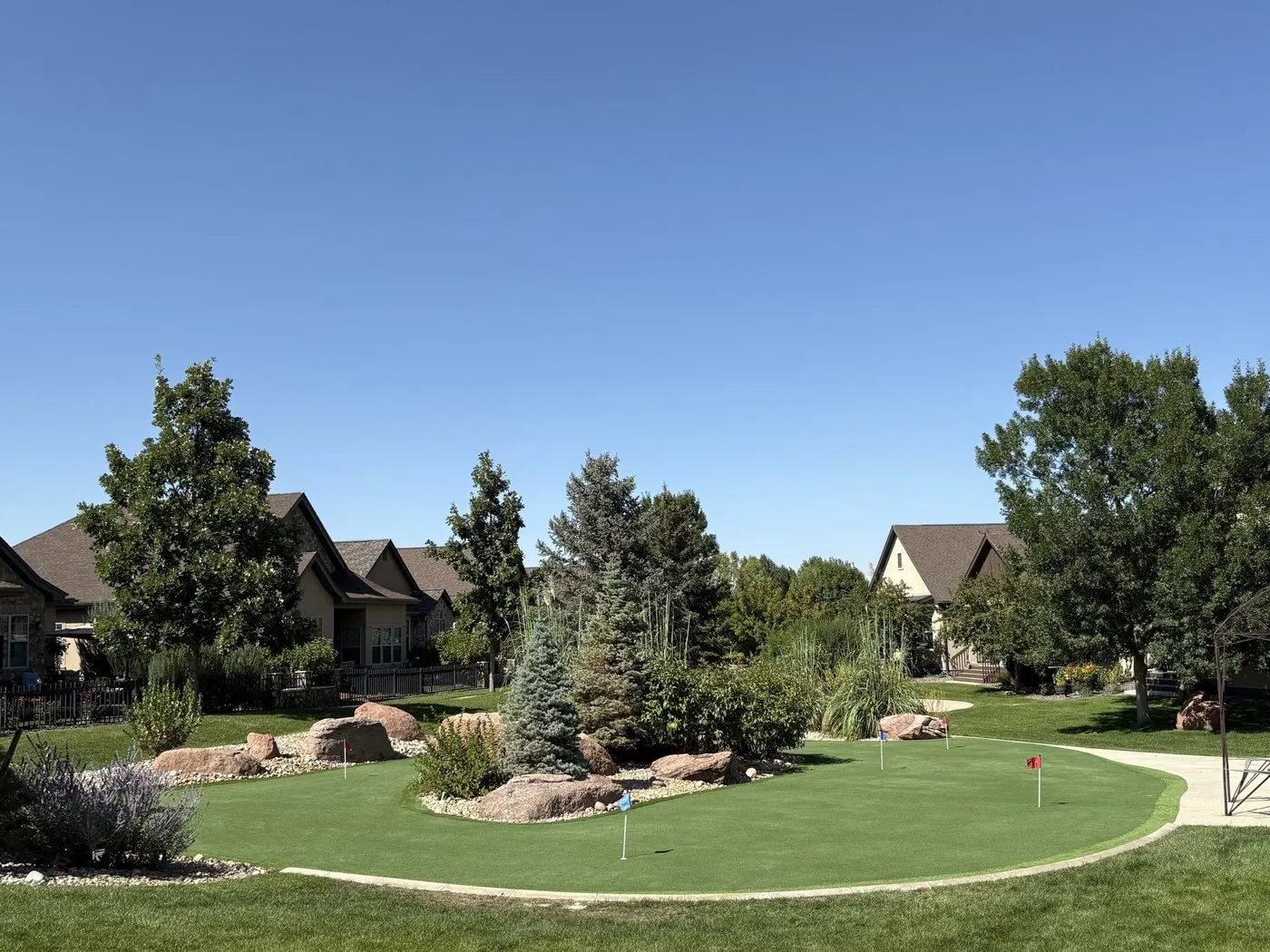 Backyard putting green seen from the street under mature trees