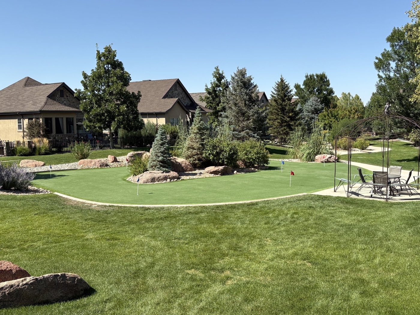 Backyard synthetic putting green set among landscaped boulders