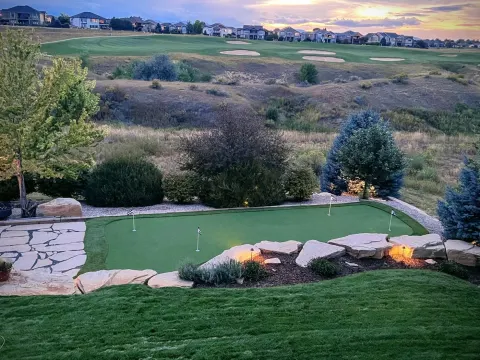 Wide view of a backyard putting green at sunset