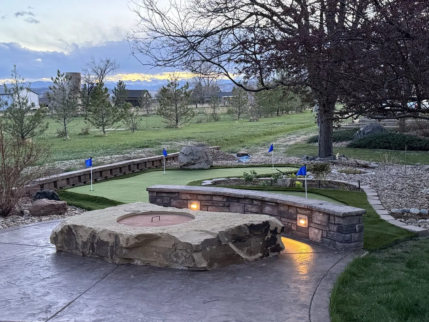 Putting green beside a fire pit and stone wall