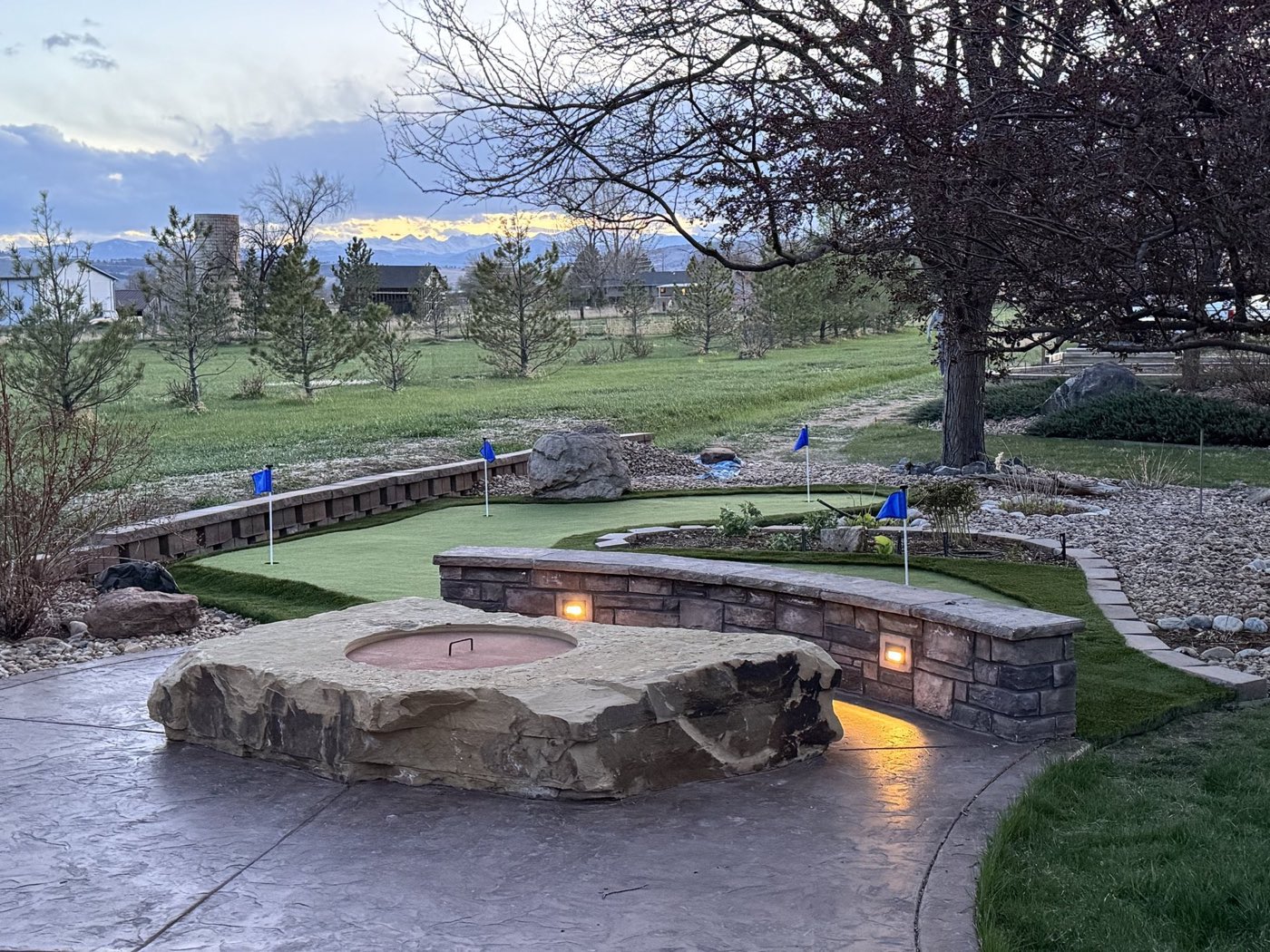 A putting green Brian built, beside a fire pit and stone wall